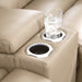 Glass of water on a beige loveseat with cup holders